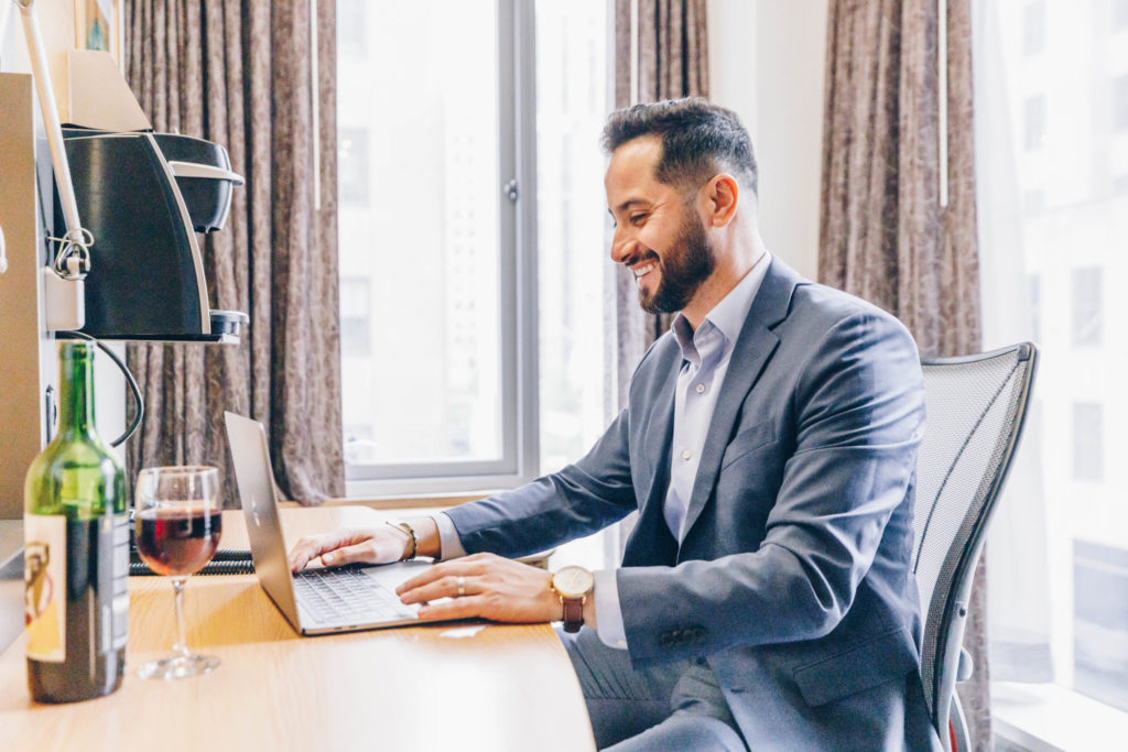 man in professional suit at in-room club quarters work desk in virtual meeting